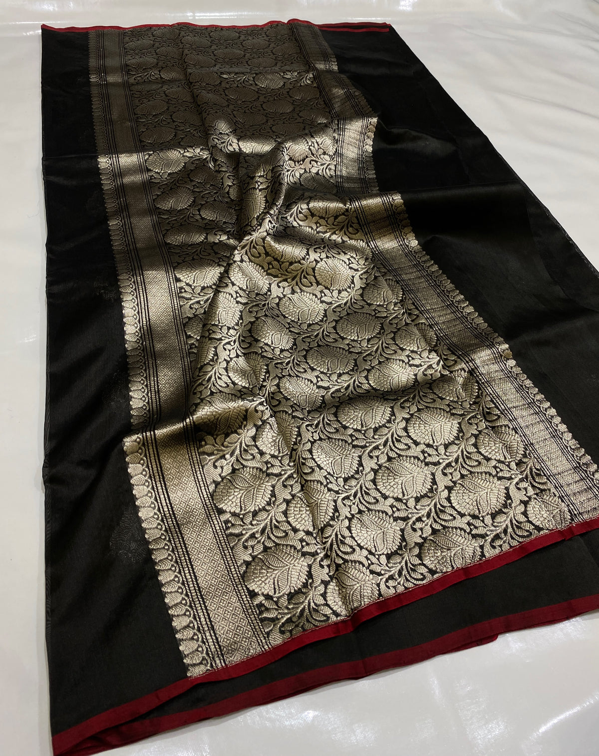 Black Chanderi silk saree displaying a richly patterned silver-champagne floral pallu and red selvedge