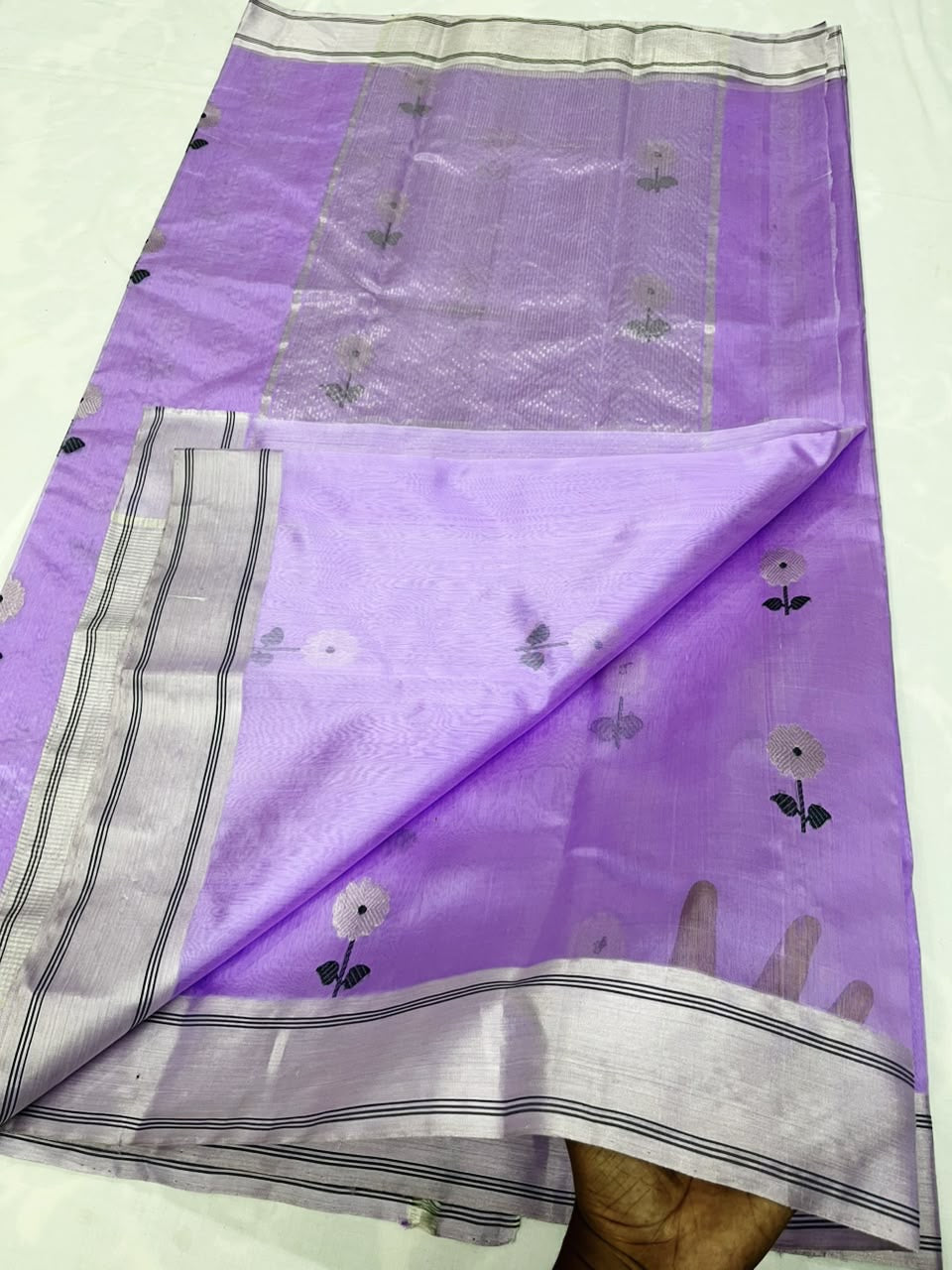 Lilac Pattu silk Chanderi saree laid open showing white floral butis, silver-toned striped border and pallu