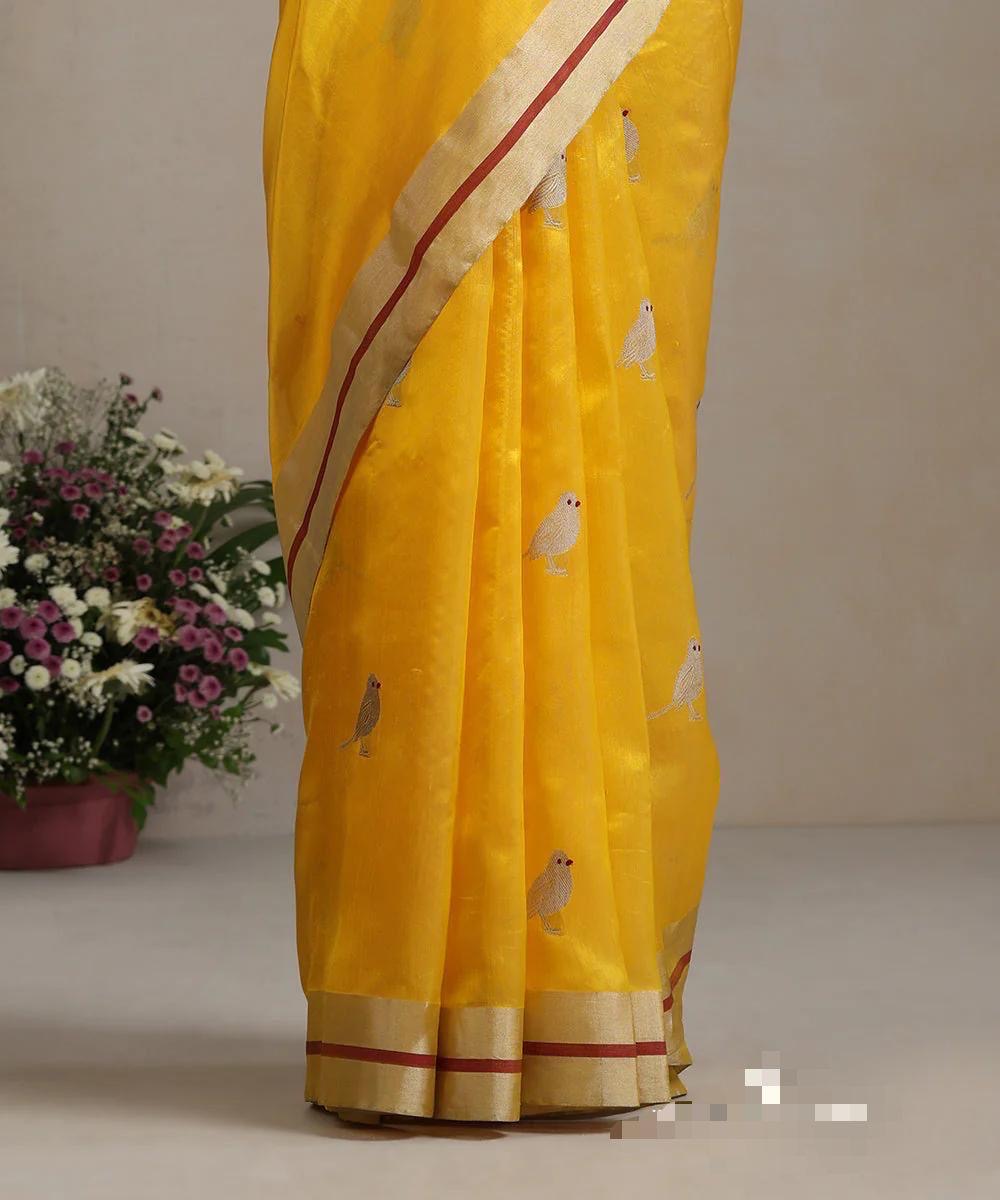 Folded marigold yellow Chanderi silk saree showing ivory bird motif and contrasting silver-gold border