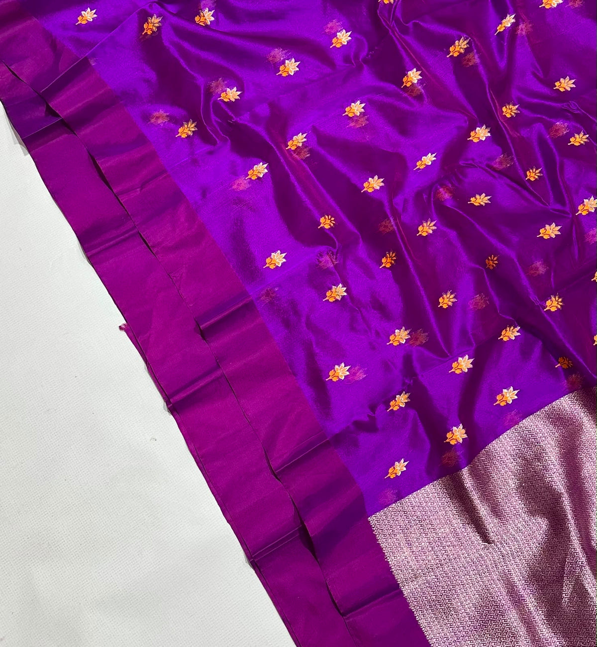 Close-up of vibrant purple Chanderi handloom silk with scattered saffron flowers, plum border and textured pallu.