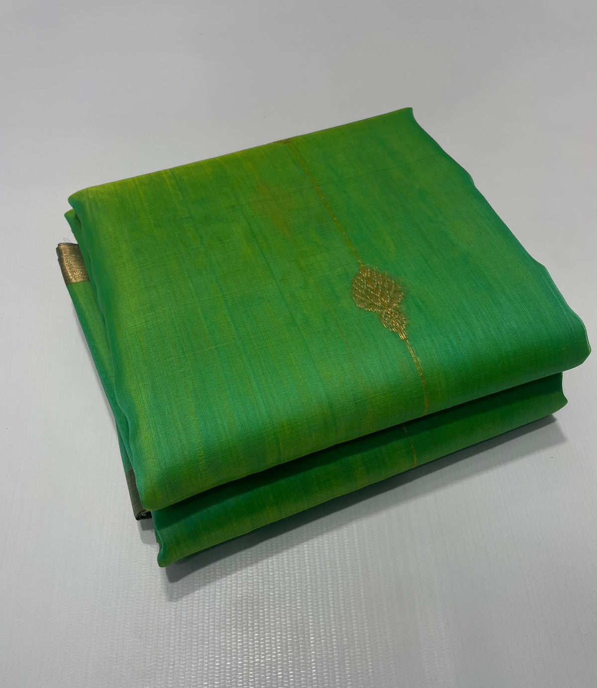 Folded sea glass green Chanderi Katan silk saree highlighting a gold-toned buti and the fresh green shot silk texture