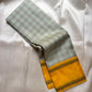 Grey and pale green checked Kanchipuram silk saree folded with mustard zari border on white fabric