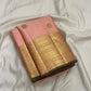 Tonal peach-pink border with layered classic-gold zari, geometric bands and small floral / leaf-like details.