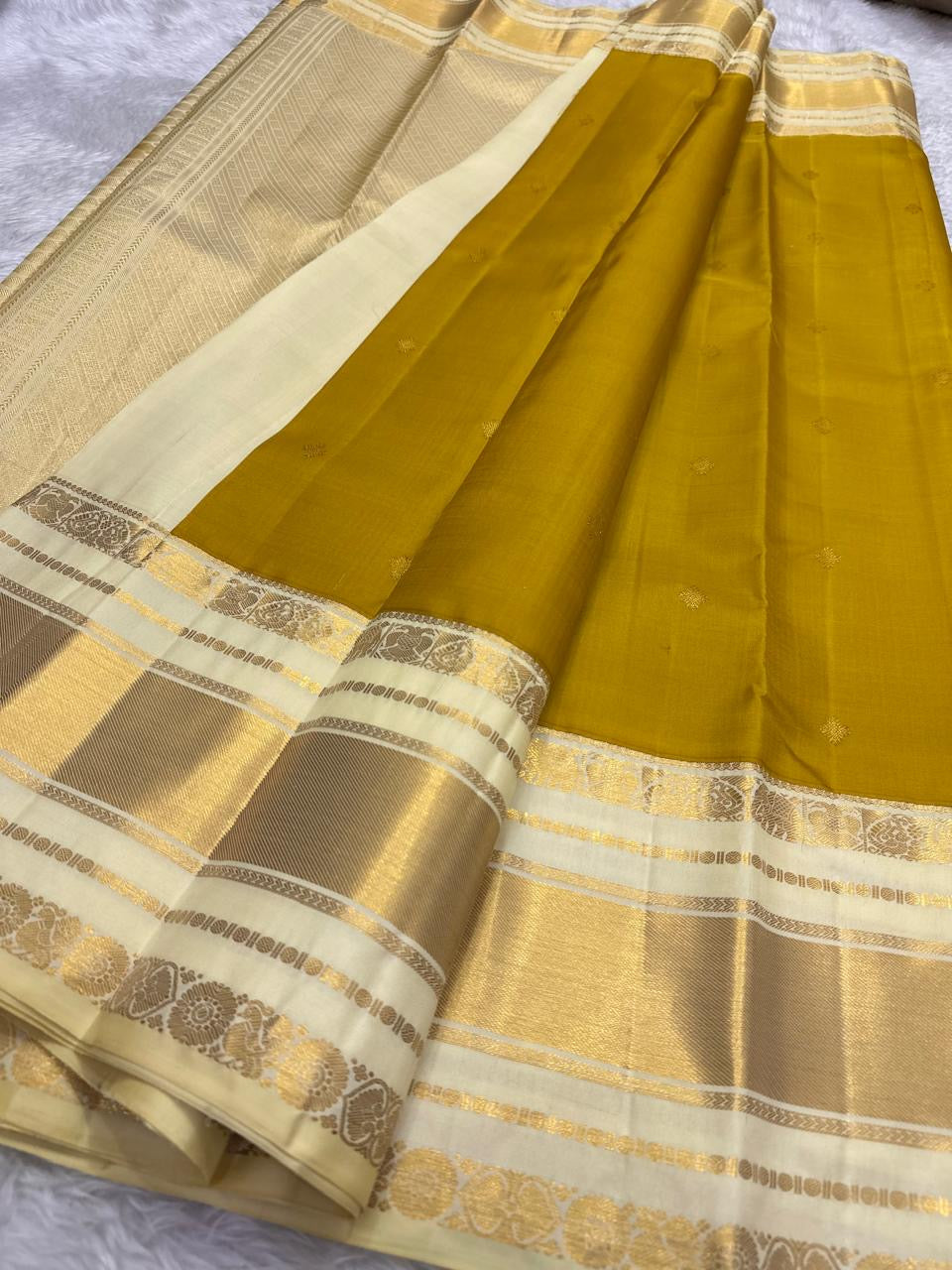Close detail of small classic-gold zari buttas spaced across the earthy Olive Turmeric Gold silk body.