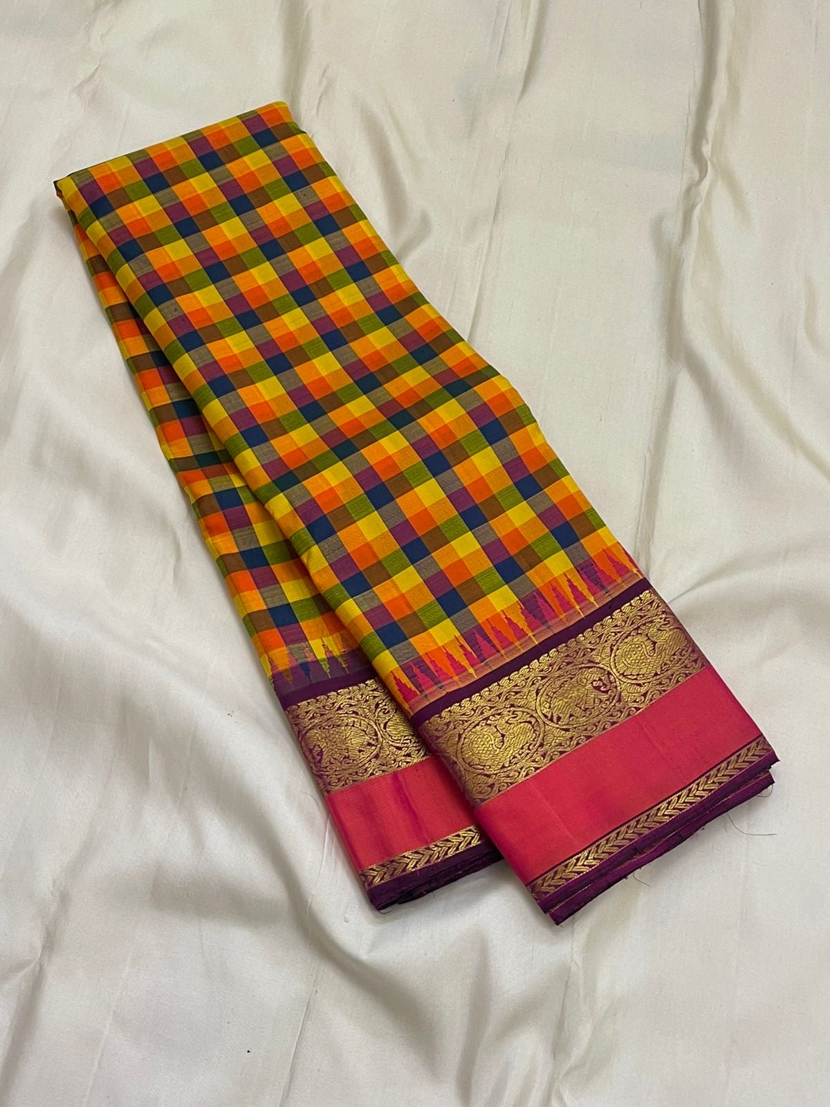 Pure Kanchipuram silk saree folded to show multicolor checks and wide pink and gold zari borde