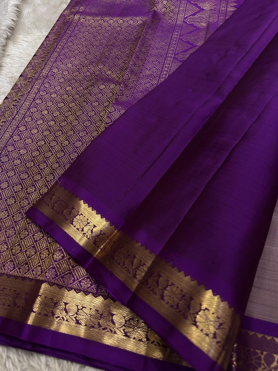 Draped mauve Kanchipuram silk saree with purple zari woven border and tassels, shown with pallu spread, available in the USA.