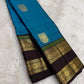 Coffee-brown rettapet border with green highlights on the turquoise blue saree.