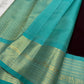 Folded coffee-brown Kancheepuram silk with small gold buttas and a contrasting fresh turquoise zari border.