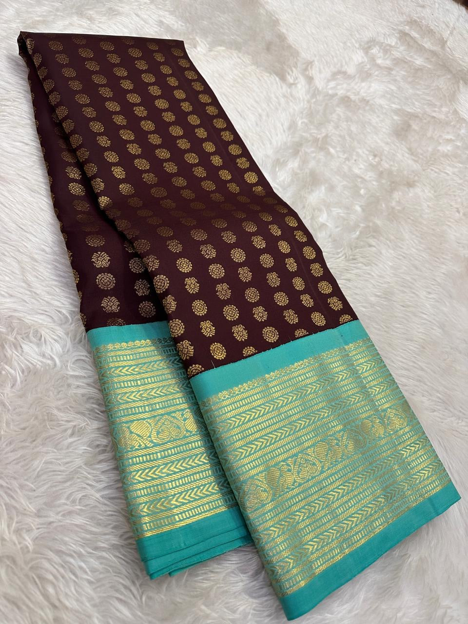 Fresh turquoise gold-zari border paired with deep coffee-brown silk in a traditional Kancheepuram saree.