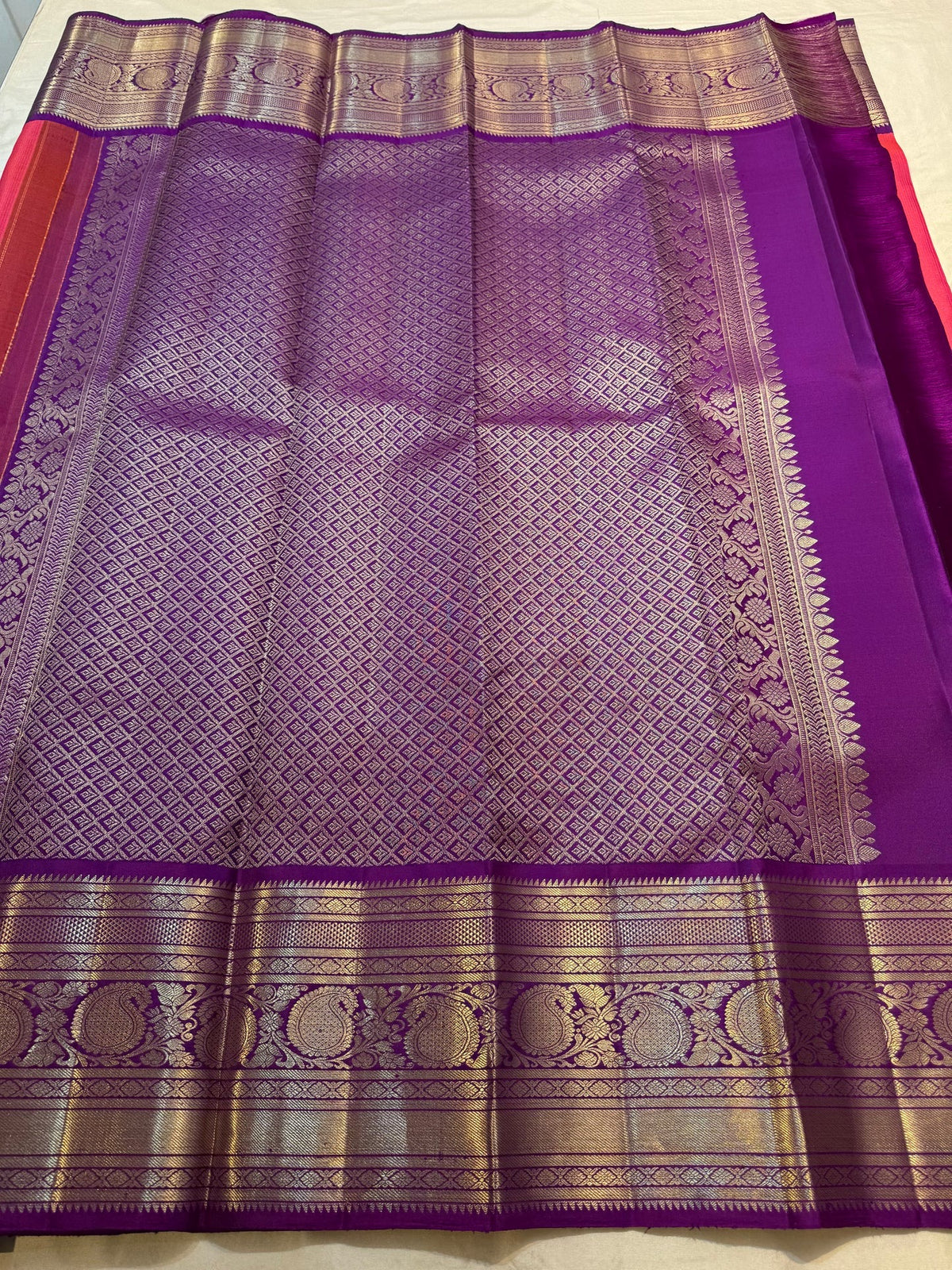 Gold and silver-toned floral buttas positioned between fine linear zari work on the silk body.