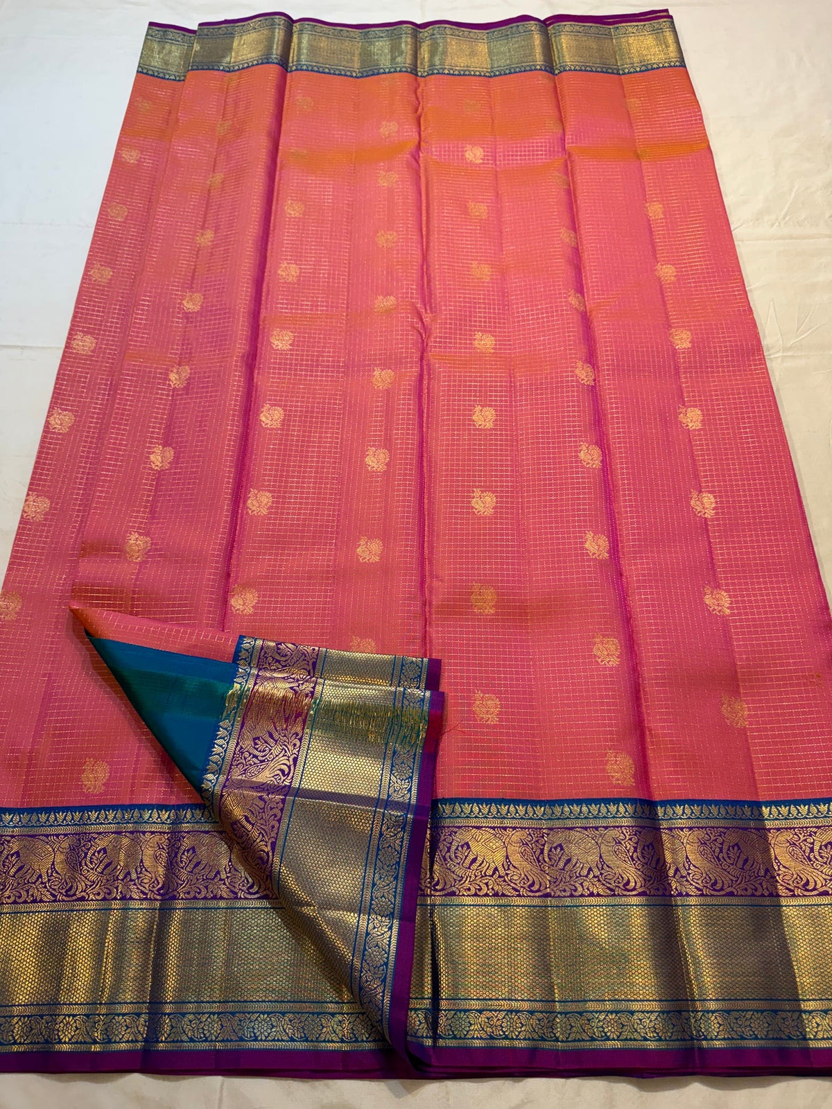 Full view of the coral sunset-orange Kanjivaram Zari Kattam saree with turquoise border