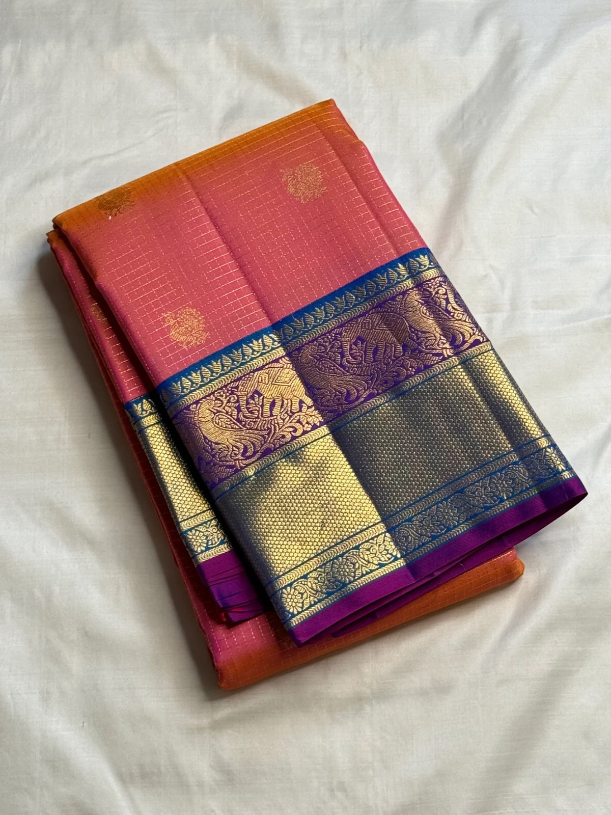Coral-orange Pure Silk Kanchipuram saree draped, showing the fine Zari Kattam grid