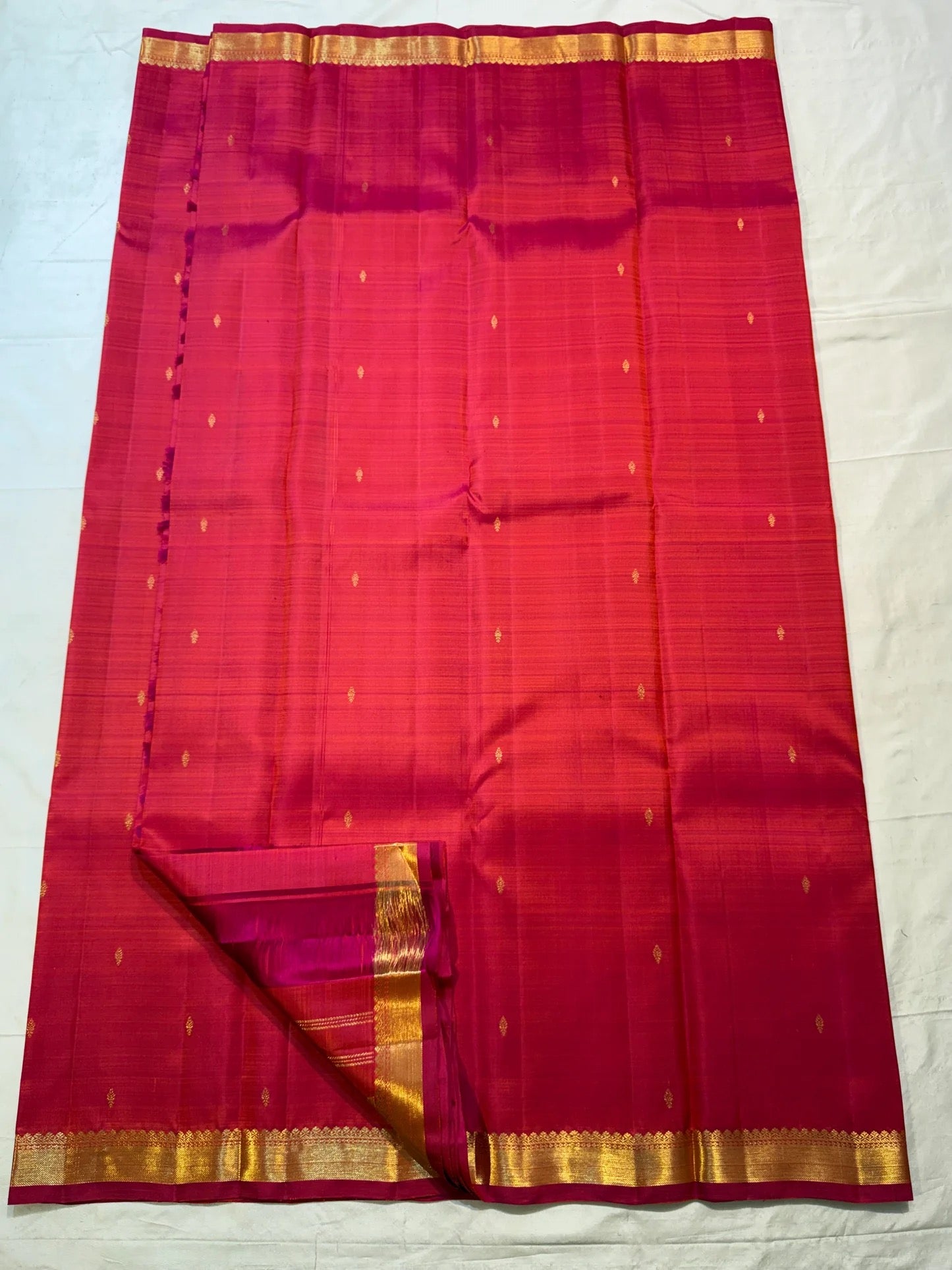 Pink-orange silk fold showing the colour shift across the handwoven surface beside gold zari