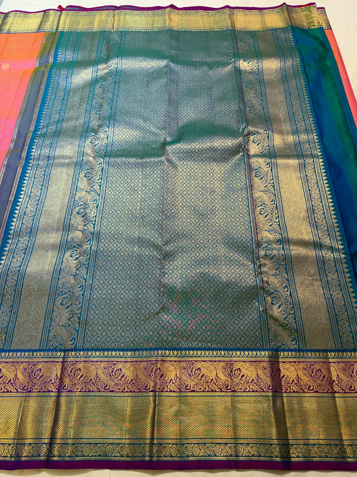 Detail of the turquoise zari border on the coral-orange Kanchipuram Zari Kattam saree