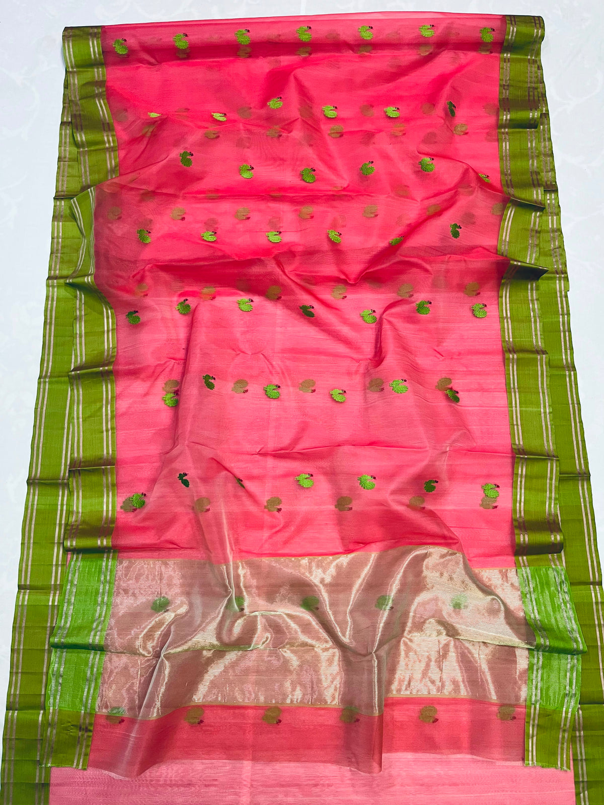 Pallu of coral pink Chanderi silk saree with green motifs and metallic zari stripes