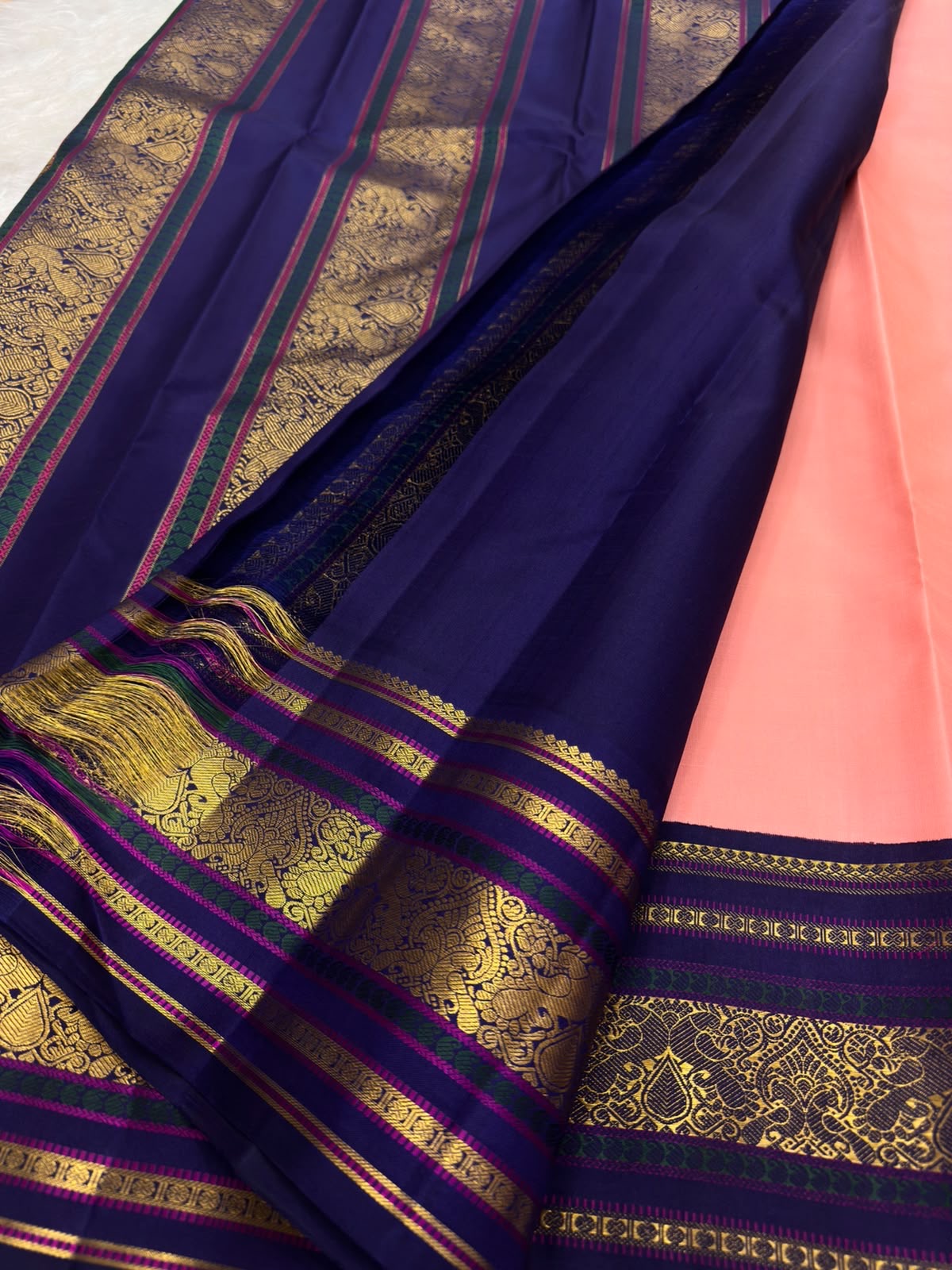 Navy-blue and rich-purple border detail, coral-pink Kanjeevaram Korvai saree