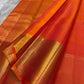 Dense gold zari buttas creating a jaal-like ornamental effect across the coral-red Kanchipuram silk.