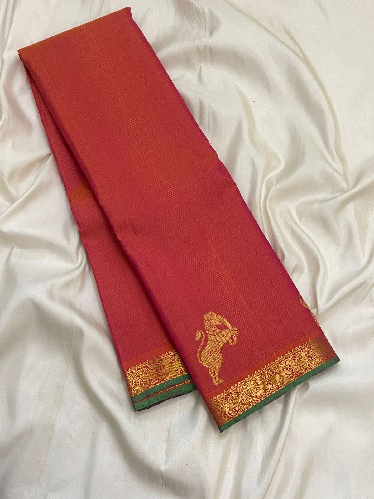 Coral pink orange Kanchi Pattu saree with fine directional Vairaoosi zari lines and green selvedge.