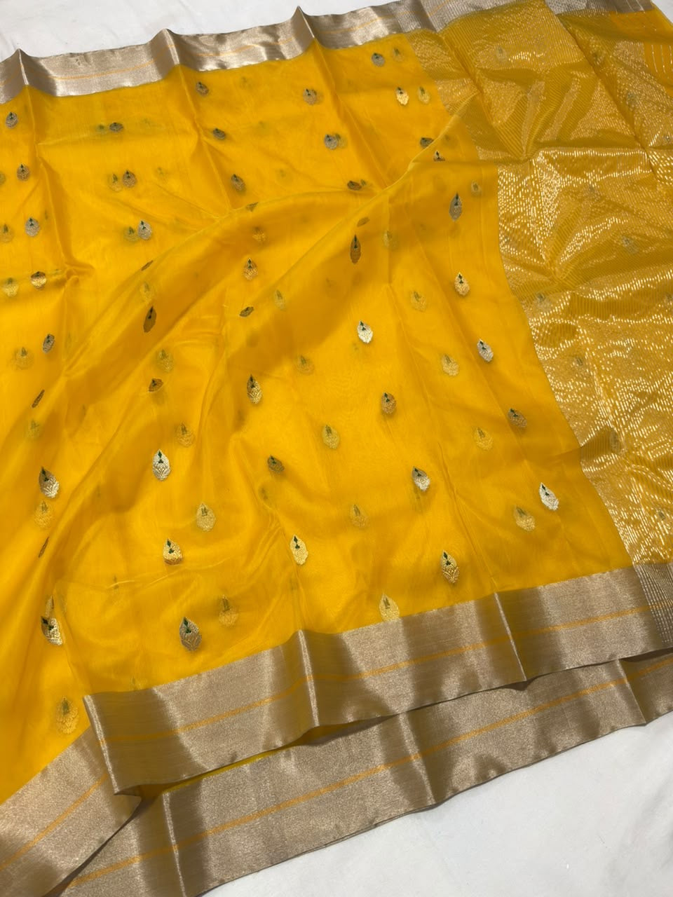 Turmeric golden yellow Chanderi Katan silk saree with small buttas and broad champagne-silver woven border