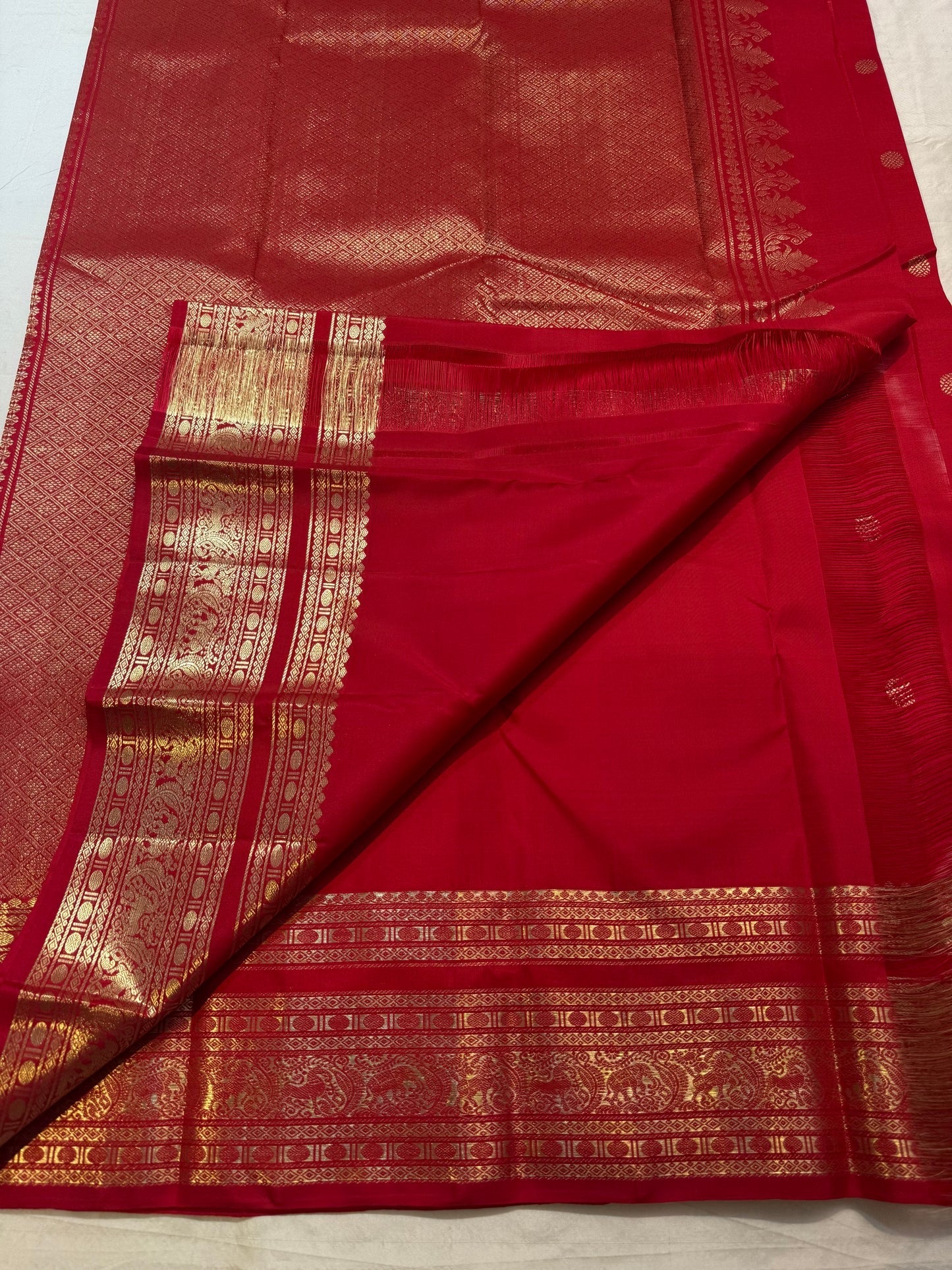 Close-up of scattered gold-zari florals on crimson Kancheepuram silk body
