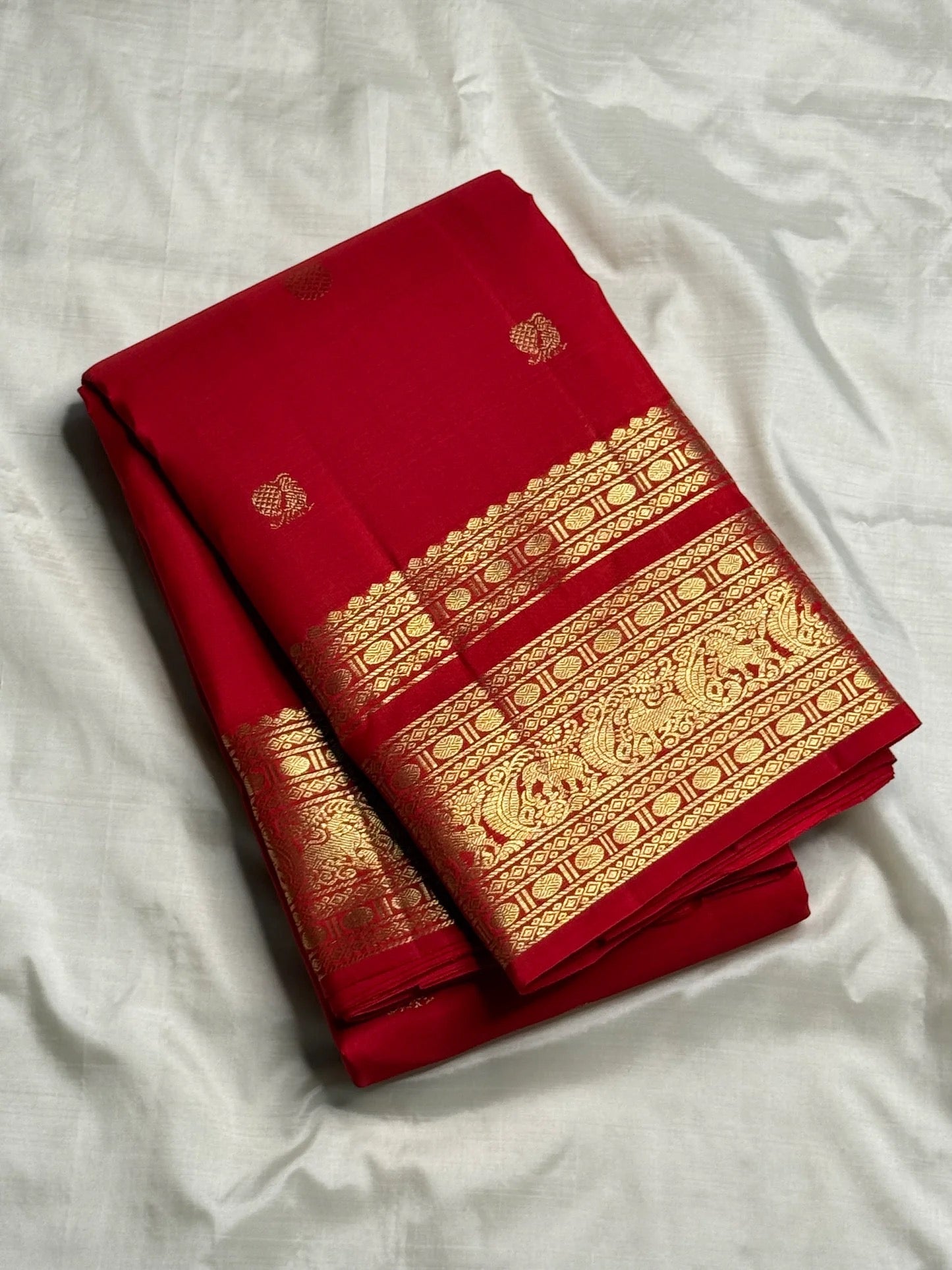 Pallu detail showing gold Varisaipet band with peacock and elephant motifs, crimson Kancheepuram saree