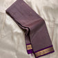 Angled fold of mauve Kanchipuram silk saree showing scattered gold buttas and a purple zari woven border edge.