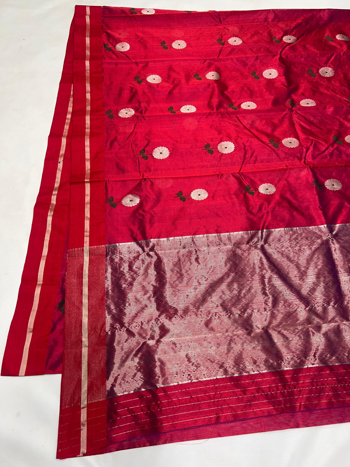 Folded Raspberry Red Chanderi saree showing the silver floral buttas and fine silver border