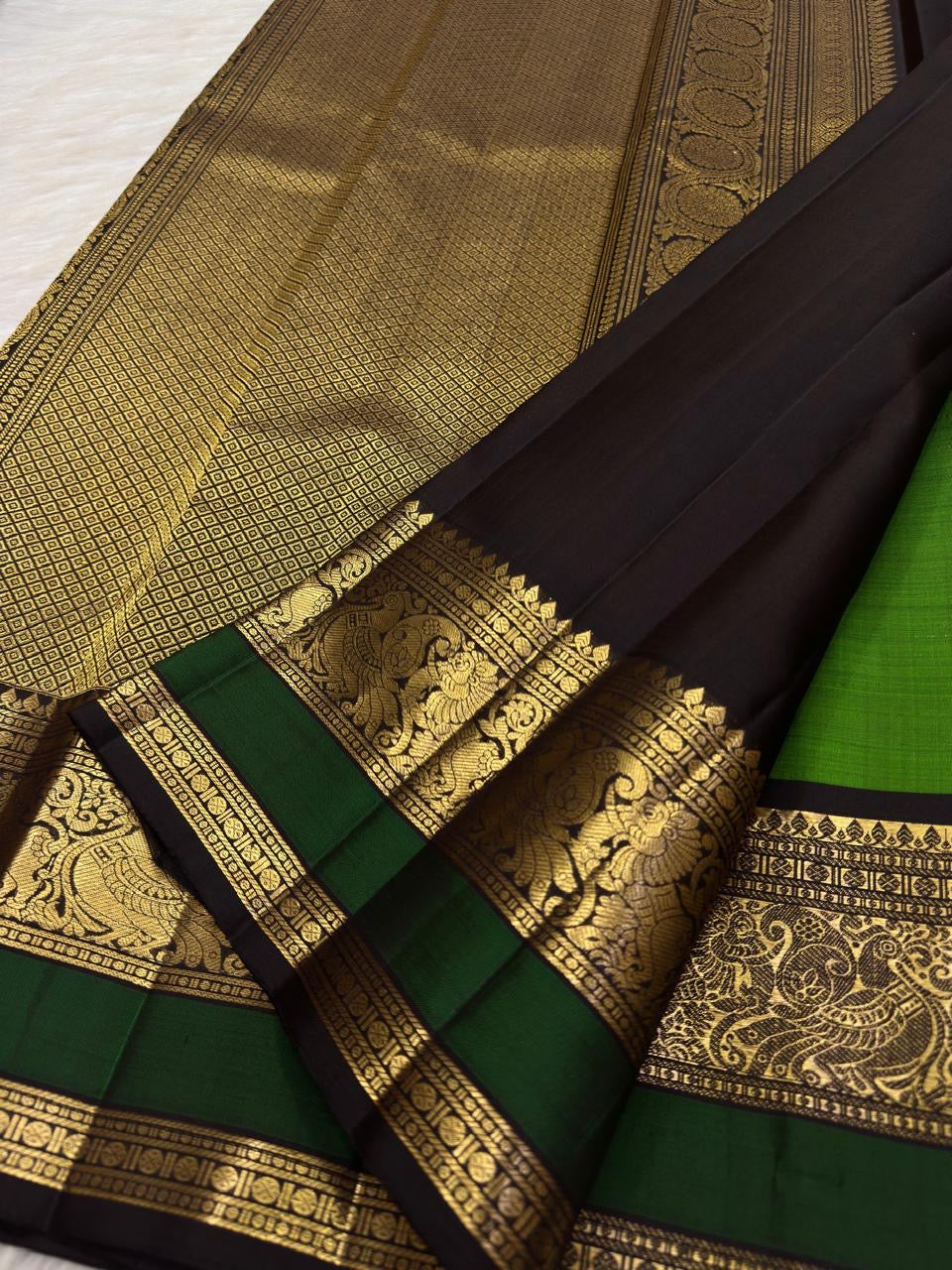 Dramatic dark contrast border with stylised Mayil and floral gold-zari work.
