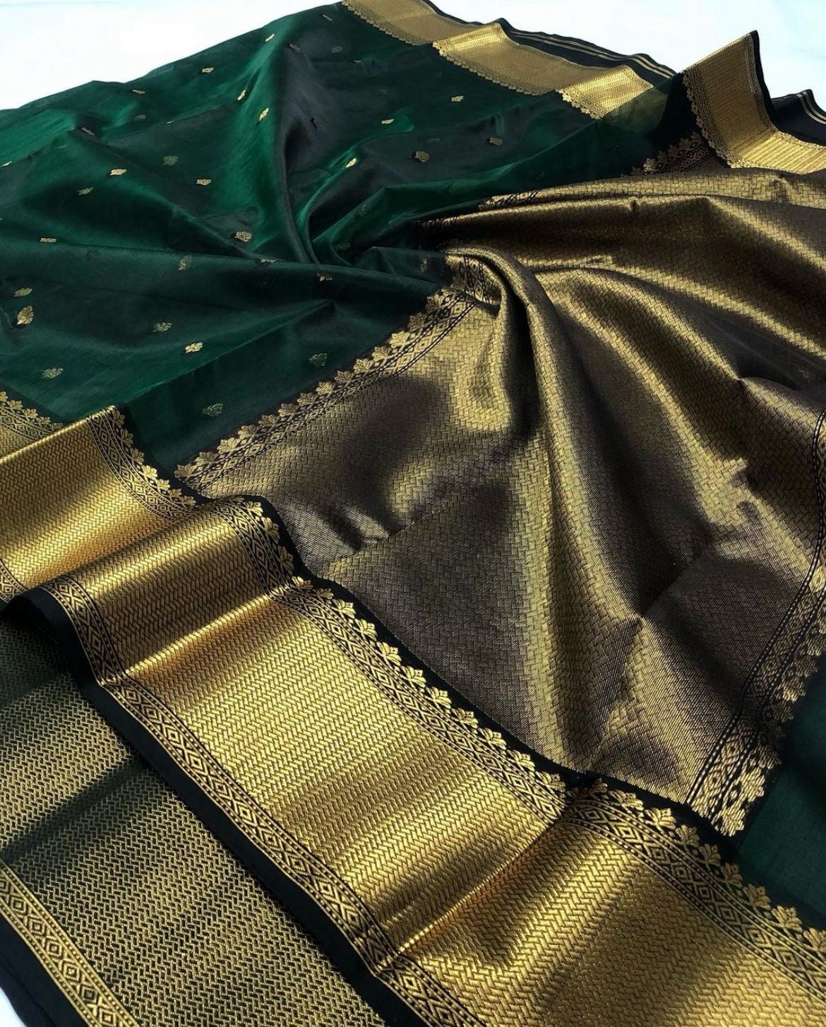 Full view of Deep Emerald Green Katan Silk Chanderi saree with gold floral buttas and broad ornamental gold border.