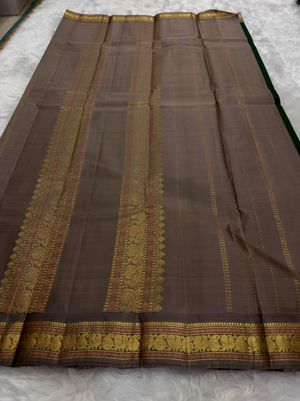 Pure Kanchipuram silk sarees stacked showing multiple color variations with zari borders
