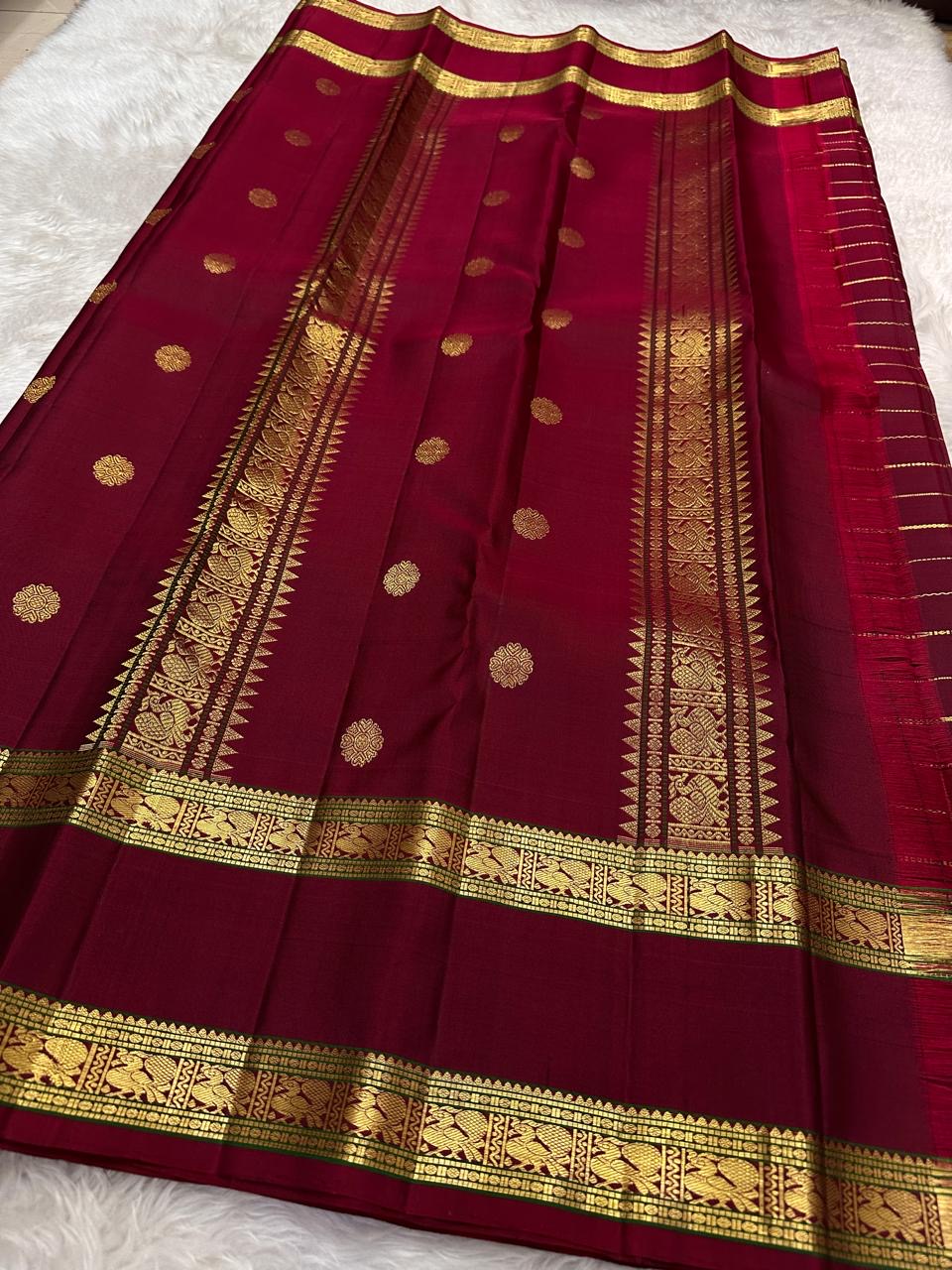 Arakku Red Kanchipuram silk saree with spaced gold buttas and fine zari lines running lengthwise.