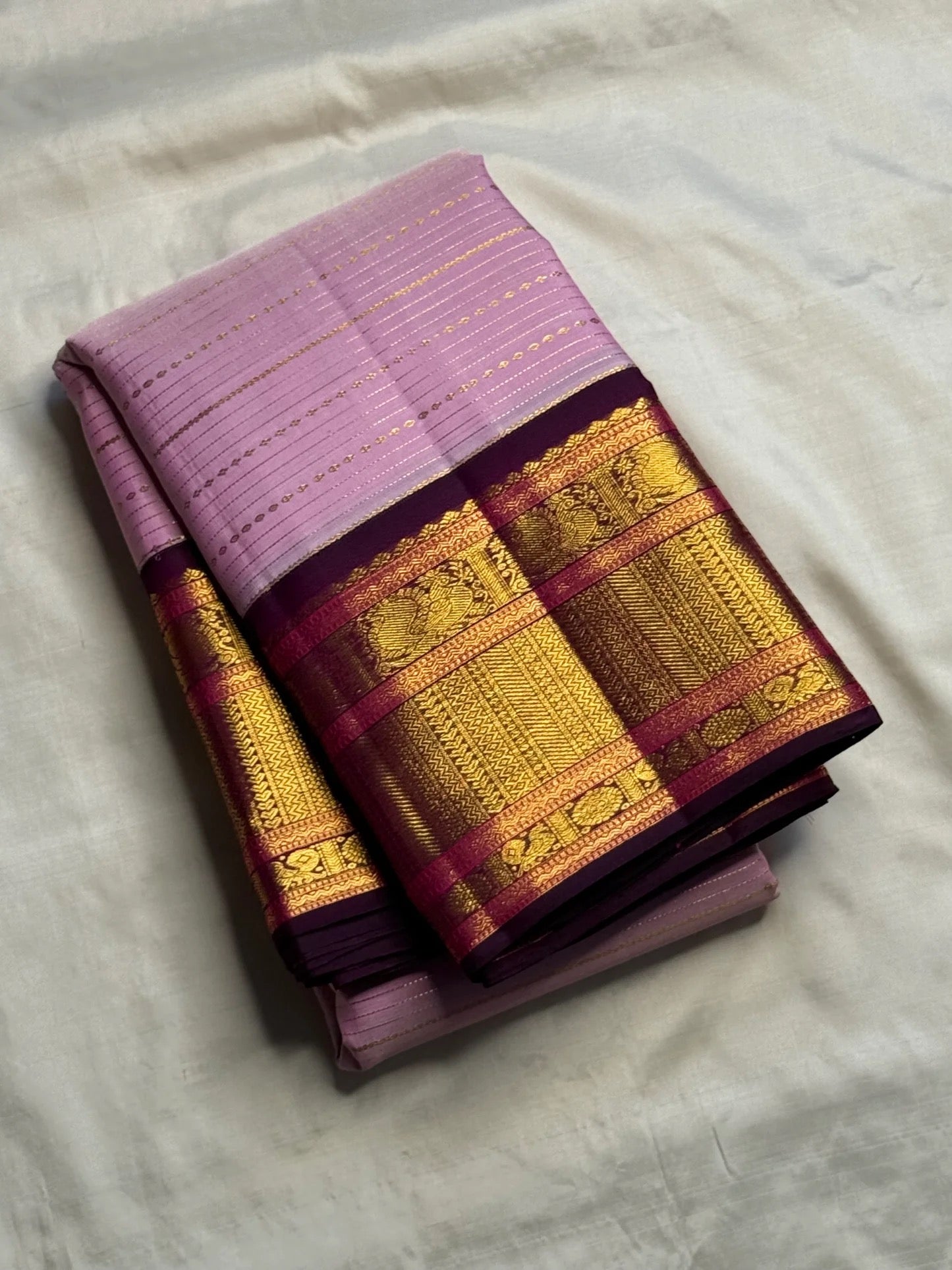 Deep Aubergine Korvai border with raspberry accents and layered gold zari on lavender Kanchipuram saree.