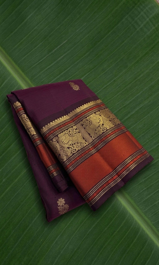 Deep aubergine Kanchipuram silk saree with antique gold zari and burnt vermilion korvai border.