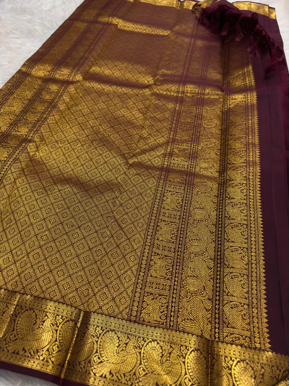 Close view of antique gold zari buttas on deep aubergine Kanchipuram silk