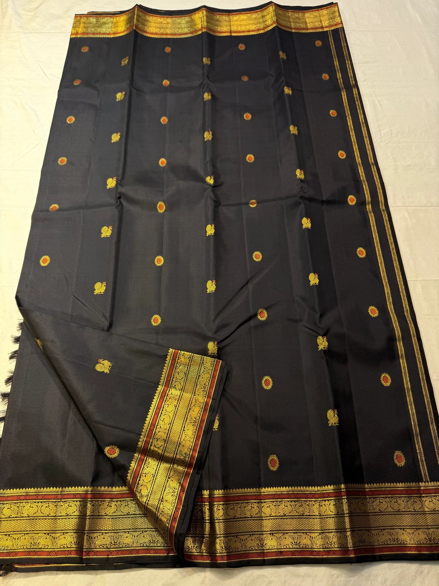 Luxury black Kanchipattu silk saree with richly woven meenakari pallu artistry.
