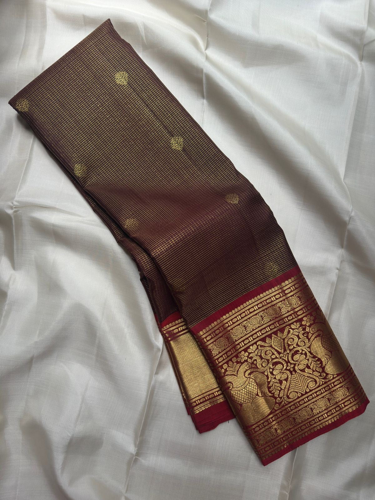 Folded Deep Coffee Brown and Arakku Red Pure Silk Kanchipuram saree showing detailed Gandaberunda gold zari border.