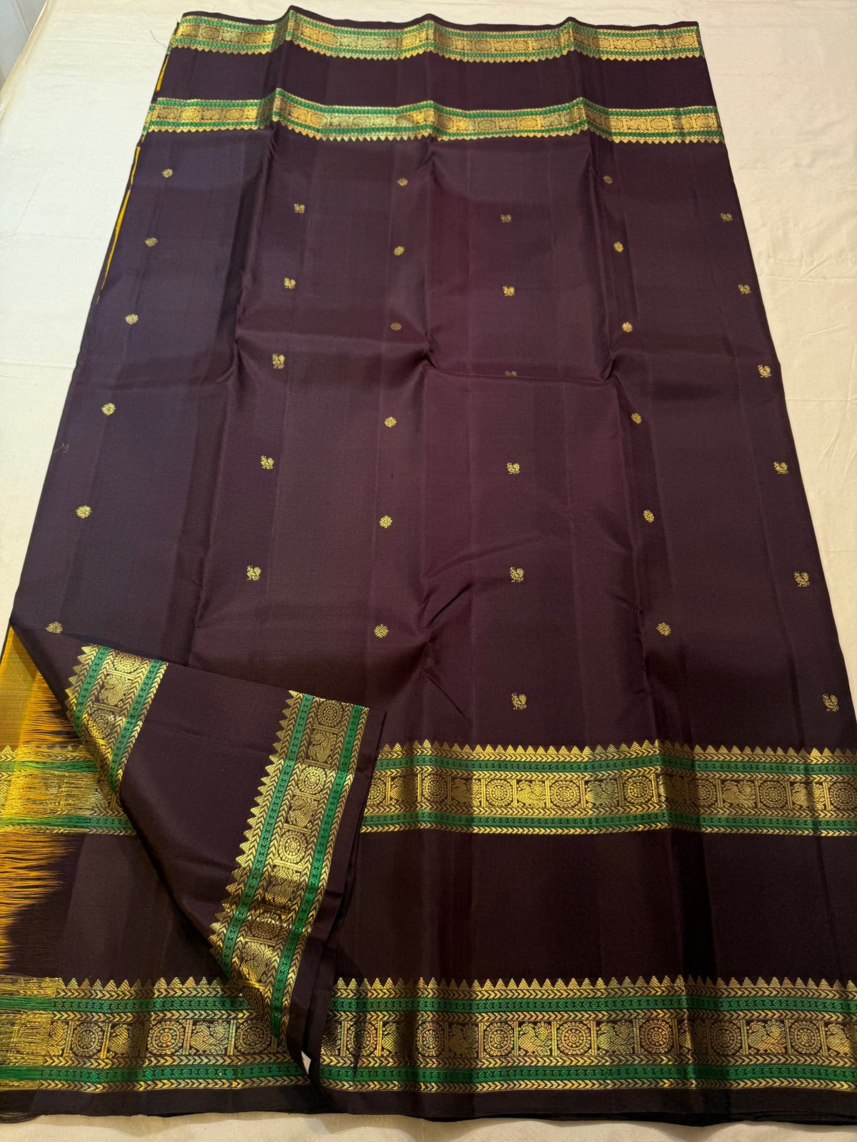 Emerald Green bands framing gold-zari registers, silk thread intertwined with the zari.