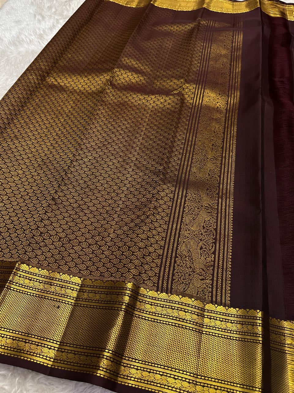 Wide grey-toned zari border framing the deep brown body of Kancheepuram Butta saree