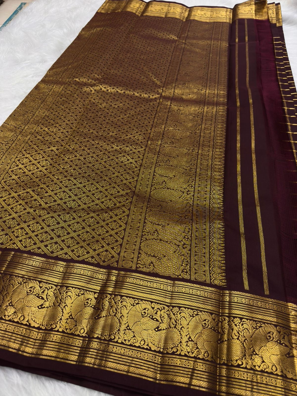 Deep brown Kanchipuram silk with structured gold zari checks and richly woven Kodi-Valli Mayil border