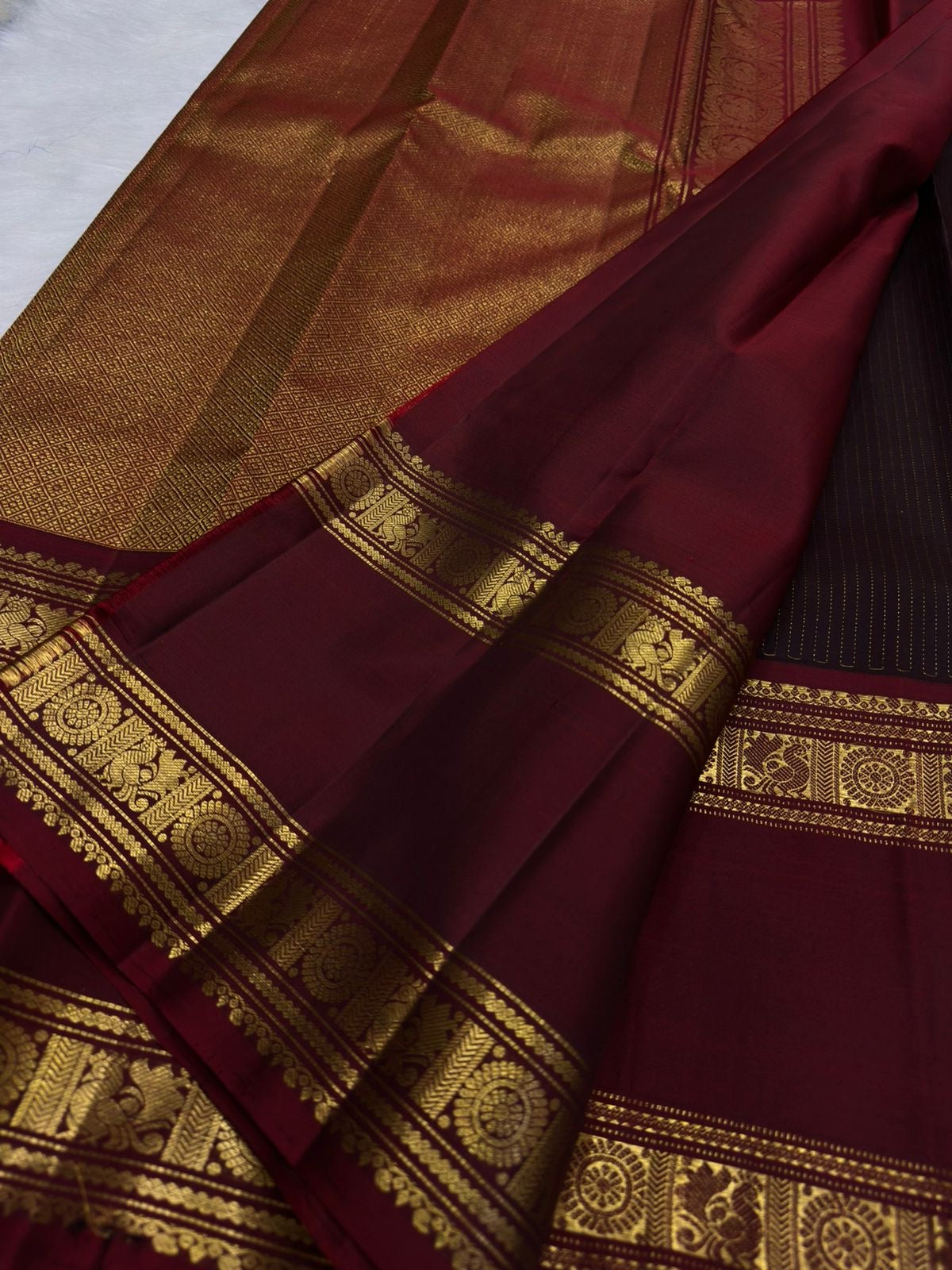 Deep brown Kanjivaram silk saree showing the Rettapet border against the fine zari-lined body.