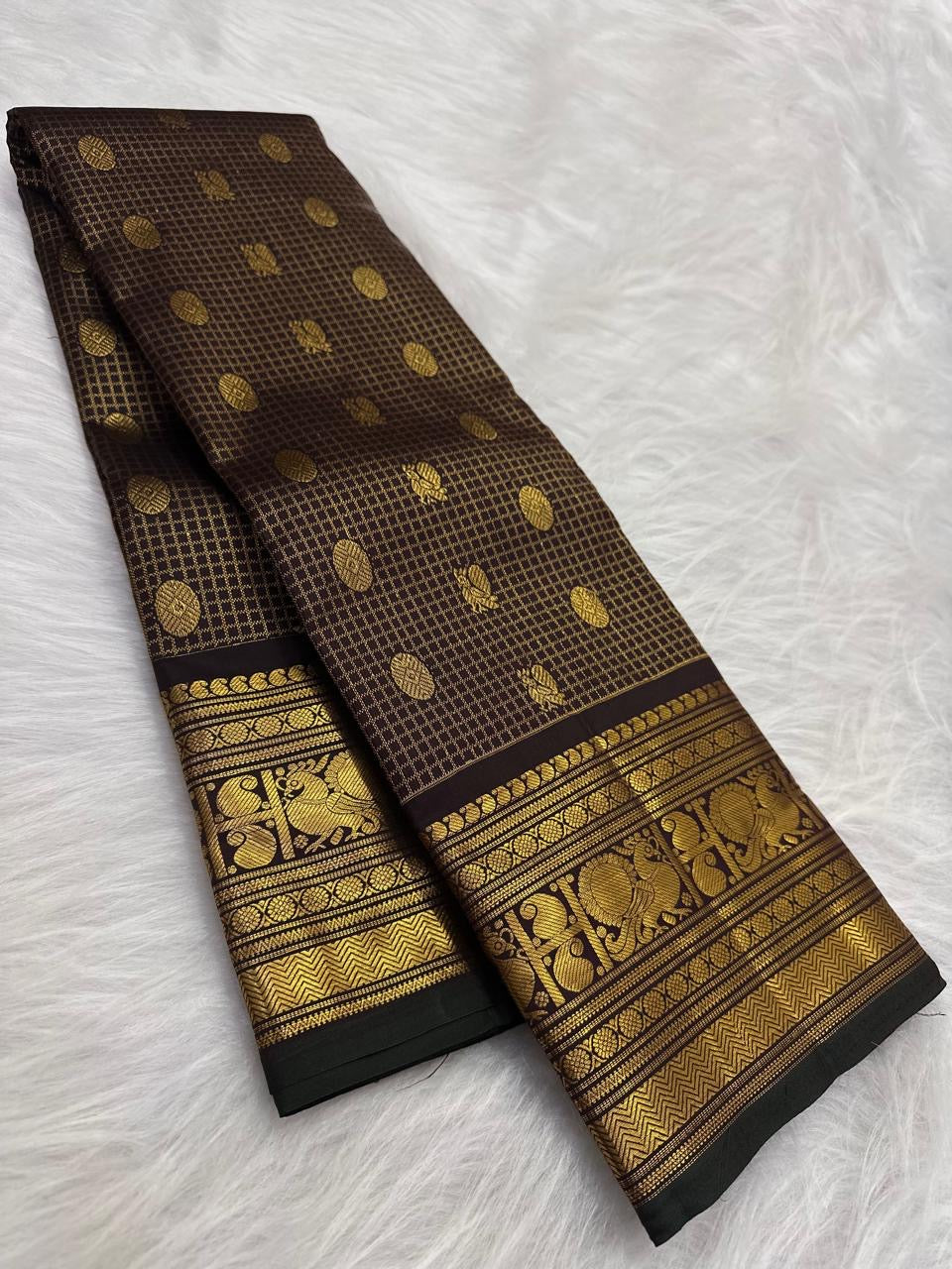 Deep brown lightweight Kanjivaram silk saree body close-up showing Zari Kattam luminous grid and large oval Mayil Chakram gold zari buttas