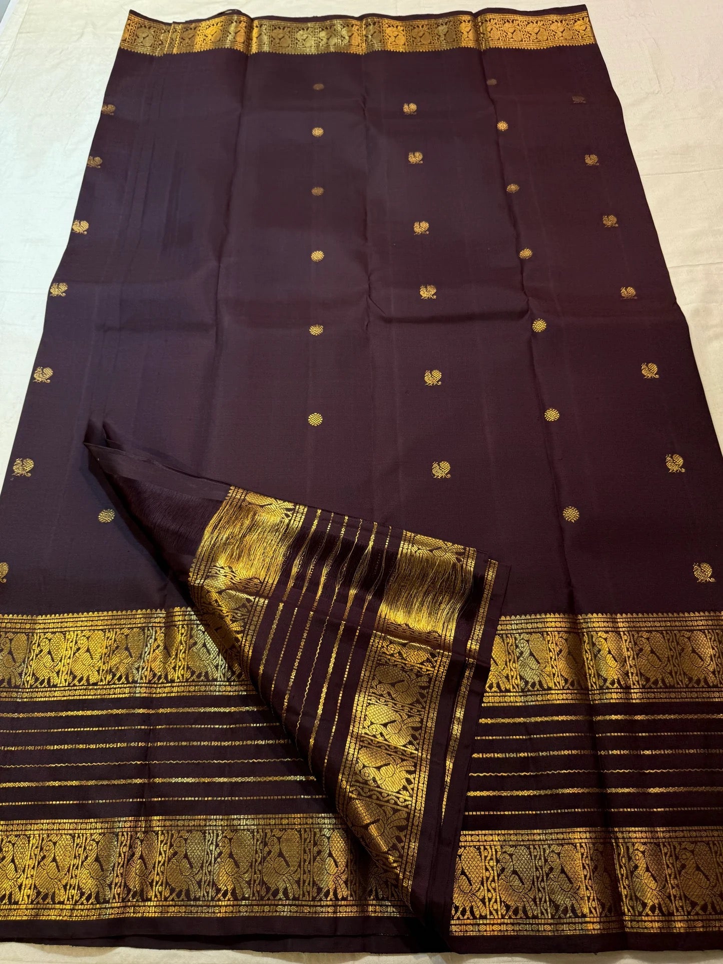 Traditional gold zari Varisaipet registers woven against dark Kanchana Brown Kanchipuram silk.