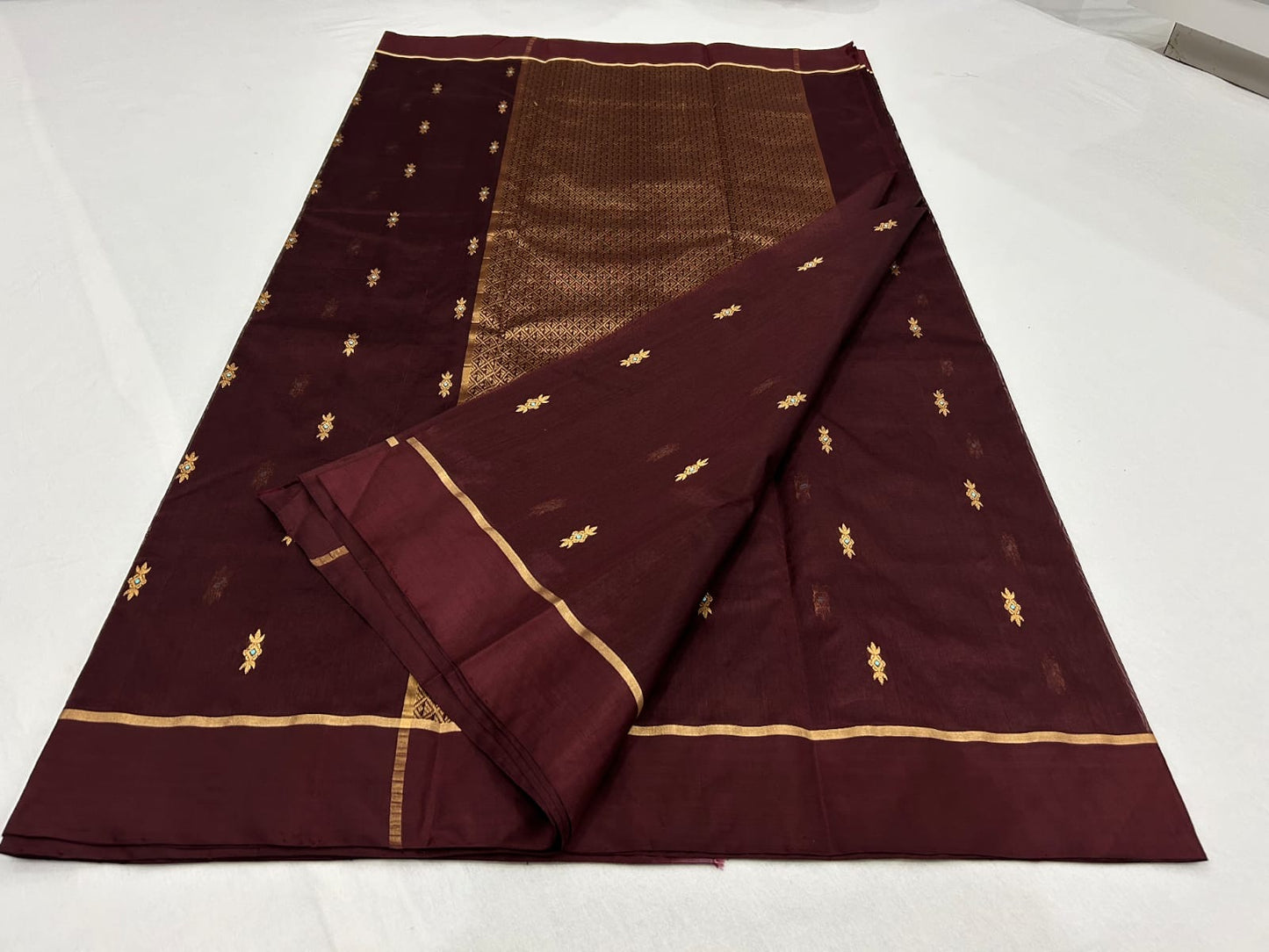 Close view of deep burgundy Chanderi fabric with petite gold zari buttas
