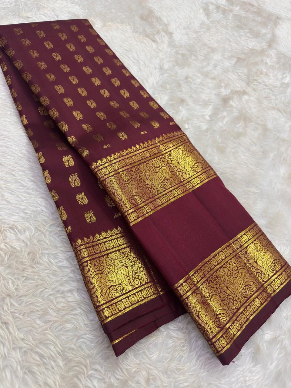 Folded Deep Burgundy Rettapet saree showing petite gold Mail buttas and ornate Yazhi zari border