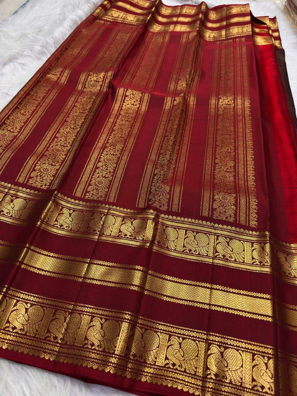Folded Deep Coffee Brown and Arakku Red Pure Silk Kanchipuram saree with intricate gold zari peacock registers.