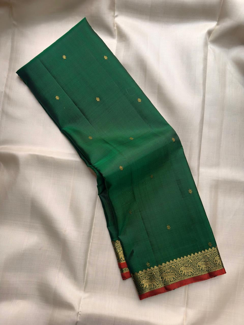 Deep Emerald Green handwoven pure silk Kanjivaram Butta saree with antique-gold zari buttas.