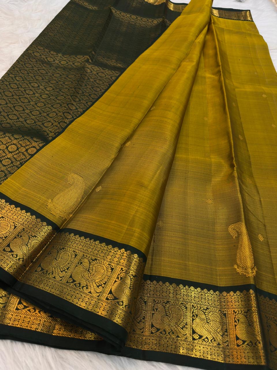 Close view of Deep Forest Green Mayil zari border on Antique Mustard Gold silk.