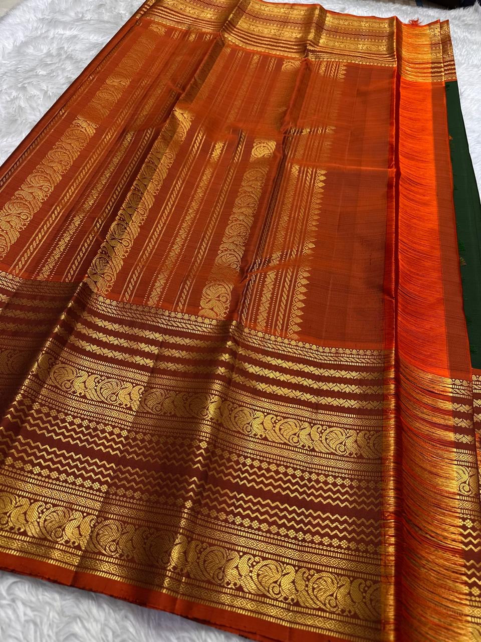 Rust orange Varisaipet border with red silk thread woven motifs on forest green Kanjipuram saree