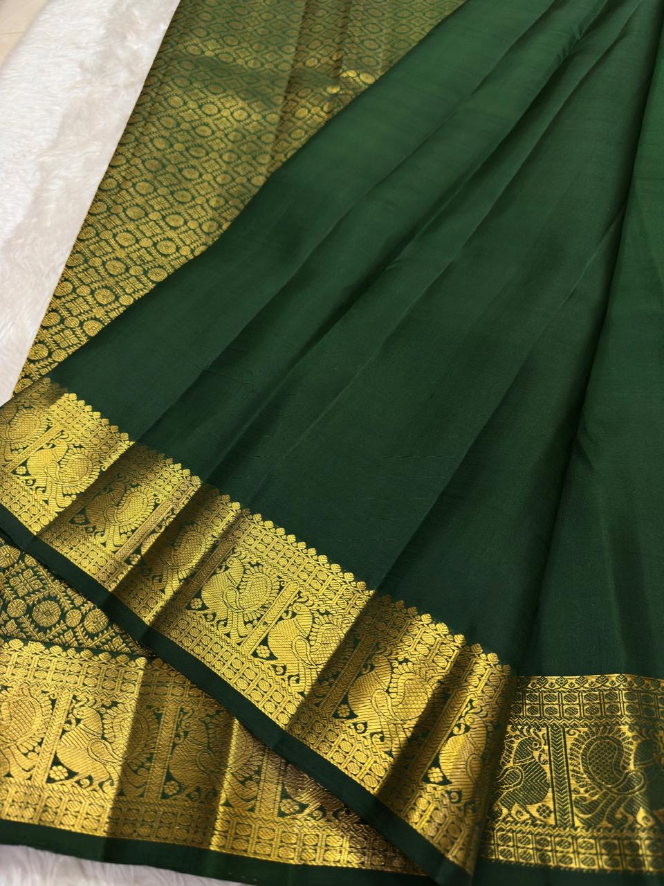 Deep green Kanchipuram Butta saree with richly detailed gold zari border