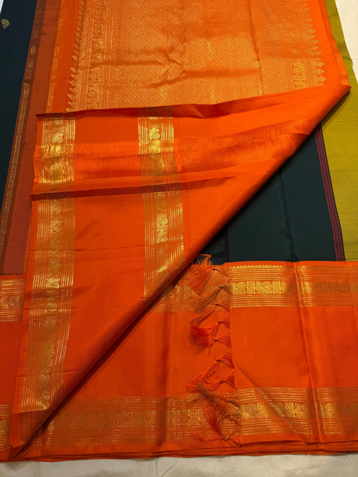 Close view of handwoven gold zari buttas on Deep Forest Green silk